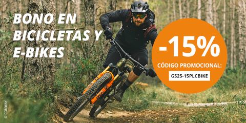 Hombre montando en bicicleta de montaña en un sendero forestal; texto en español ofrece 15% de descuento en bicicletas y E-bikes con el código promocional GS25-15PLCBIKE.