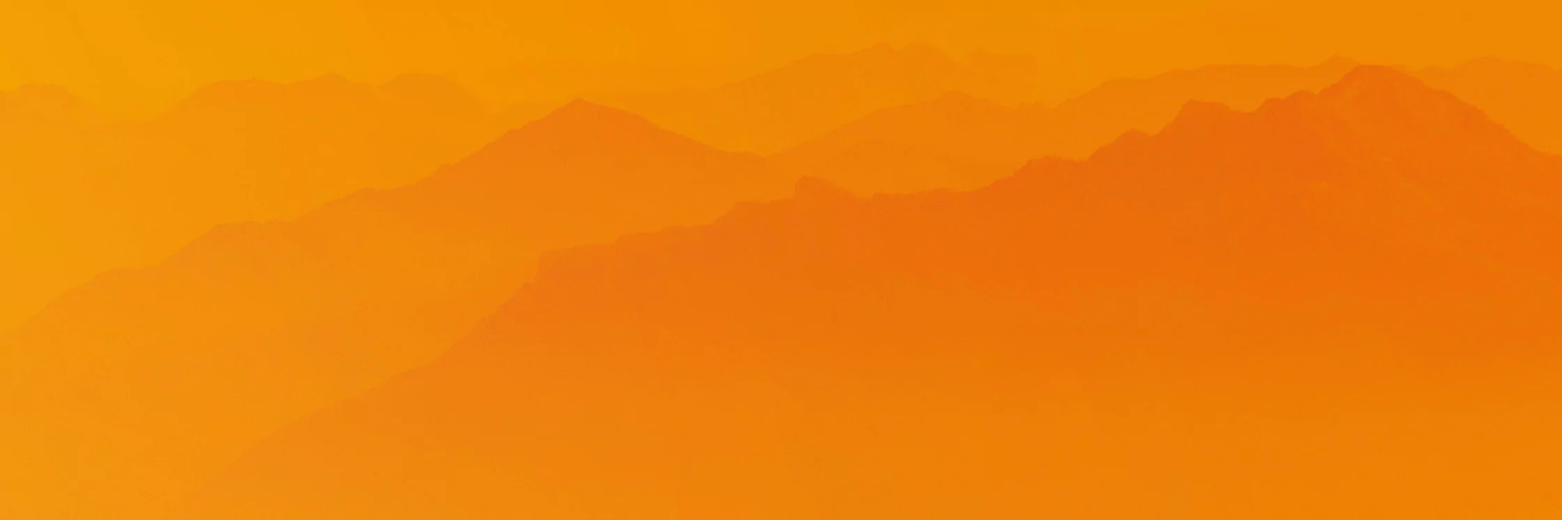 Die Silhouetten der Bergketten verschwinden in der Ferne unter einem warmen, orangefarbenen Himmel mit Farbverlauf und schaffen eine ruhige und heitere Landschaft.