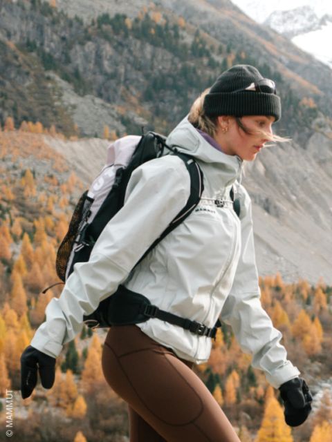 Una mujer camina en la naturaleza en otoño, vestida con una chaqueta, un gorro, 