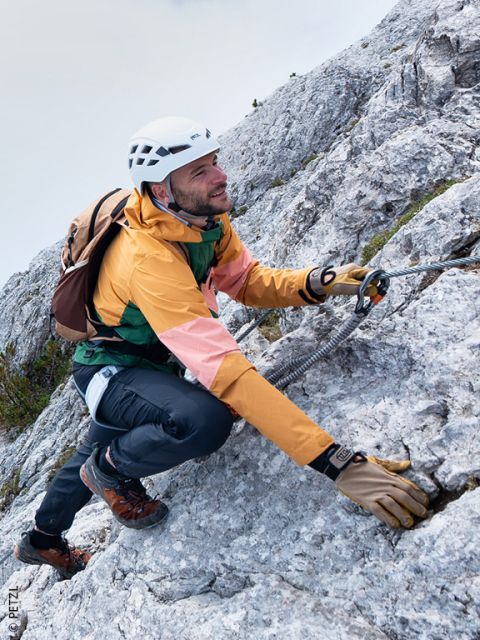 Un hombre con equipo de escalada sube por la ladera rocosa de una montaña, sujet